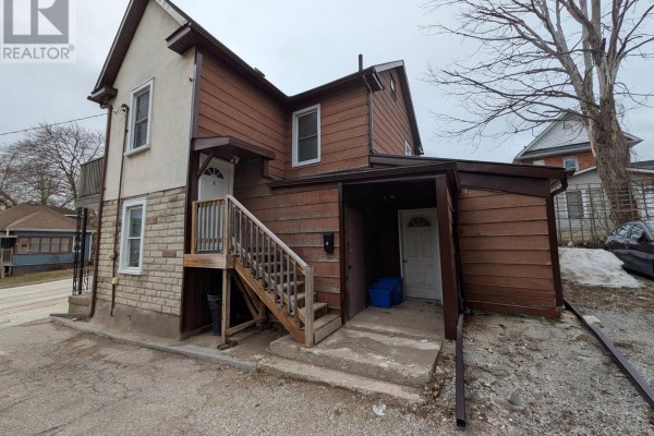 Rear exterior of the multi-family home with wooden siding and external staircases. - 87 Maple Avenue, Barrie
