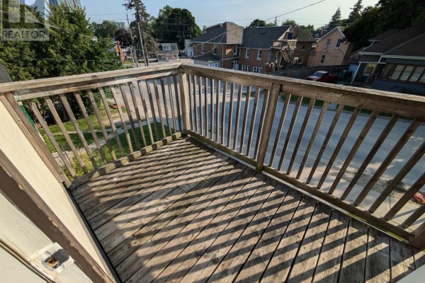 Wooden deck with railings overlooking a street with houses and trees. - 87 Maple Avenue, Barrie