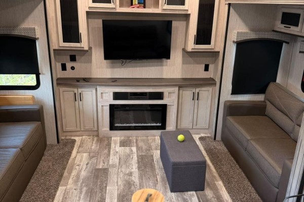 Living room with grey couches, electric fireplace, large TV, and light wood laminate flooring. - 87 Maplesue Point Drive, Molega Mines