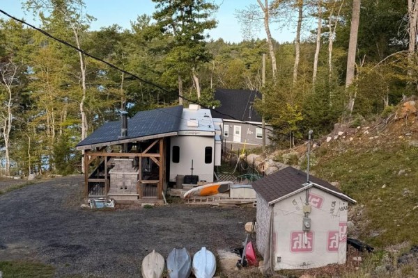 Exterior view of trailer and shed on wooded property with lake in background. - 87 Maplesue Point Drive, Molega Mines