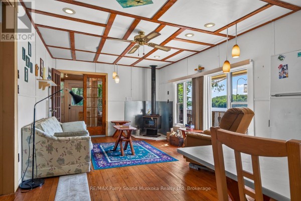 Living room with wood stove, floral sofa, and water view - 87 Millies Road Seguin