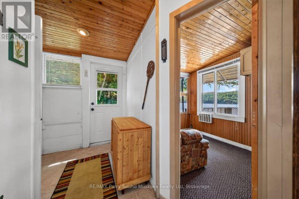 Rustic room with wooden ceiling, lake view, and patterned armchair - 87 Millies Road Seguin