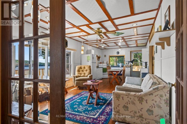 Living room with floral sofa, armchair, dining set, and wood-paneled ceiling - 87 Millies Road Seguin