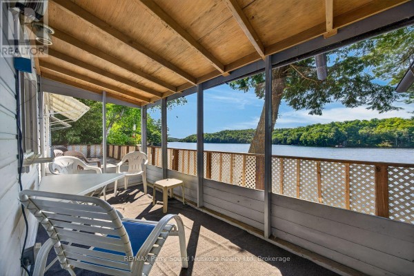 Covered porch with lake view, outdoor seating, and picnic table - 87 Millies Road Seguin