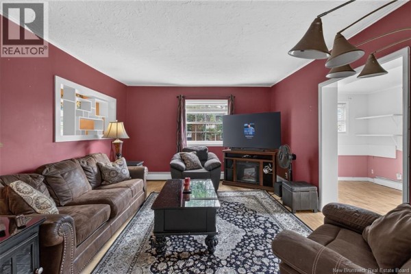 Living room with dark brown leather sofas, a black coffee table, and red walls. - 87 Milner Road, Moncton