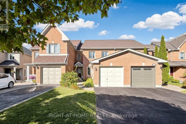 Exterior view of brick townhouses with attached garages and manicured lawns. - 87 Primeau Drive, Aurora