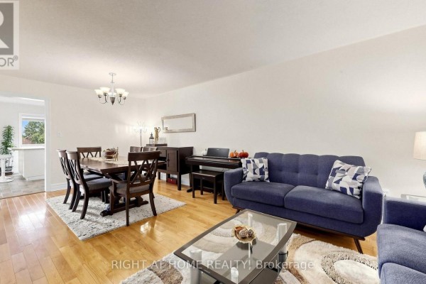 Living and dining room with hardwood floors, blue sofa, dining set, and piano. - 87 Primeau Drive, Aurora