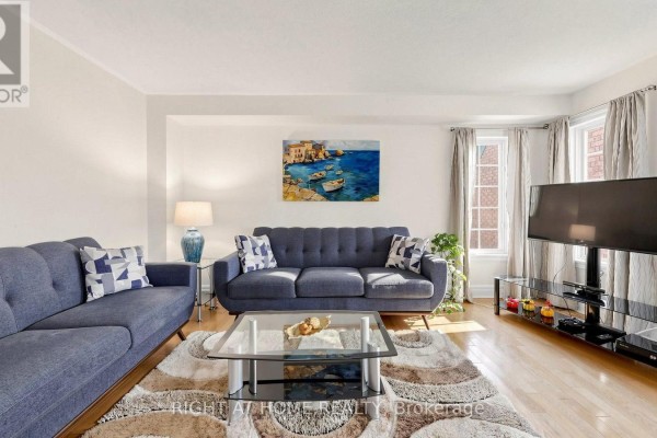 Living room with blue sofa, coffee table, artwork, television, and side table. - 87 Primeau Drive, Aurora