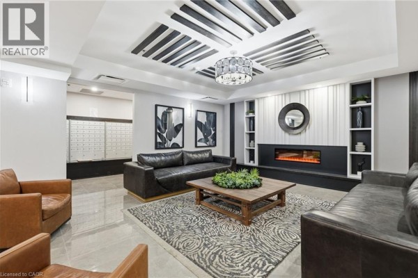 Apartment building lobby with dark leather sofas, a coffee table, fireplace, and mailboxes. - 870 Queenston Road Unit# 416, Stoney Creek
