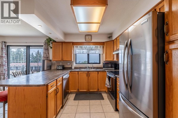Kitchen with light wood cabinets, stainless steel appliances, and a large island. - 8704 Purves Road Unit# 8, Summerland