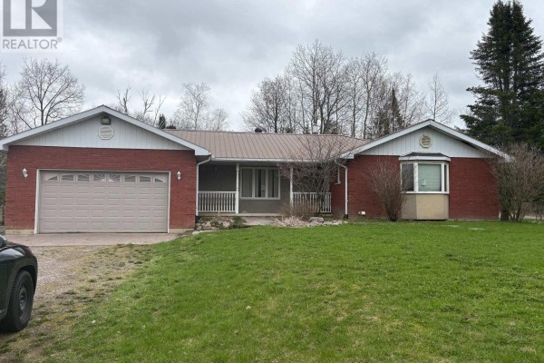 Front exterior of a brick house with a metal roof and an attached garage on an overcast day. - 8709 8th Line, Essa