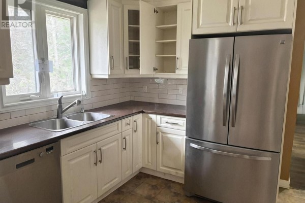 Kitchen corner with a double sink, dishwasher, white cabinets, and stainless steel refrigerator. - 8709 8th Line, Essa