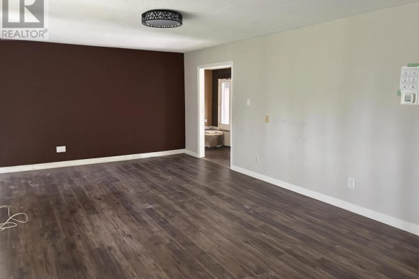 Living room with dark wood laminate flooring, a dark brown accent wall, and a doorway to another room. - 8709 8th Line, Essa