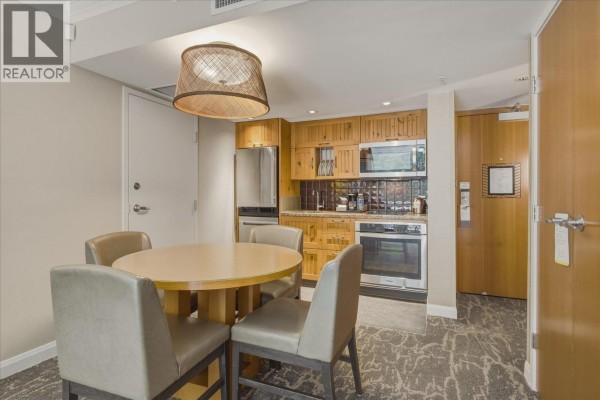 Small dining area with a round wooden table and four grey chairs next to a kitchenette. - 871/872 4090 Whistler Way, Whistler