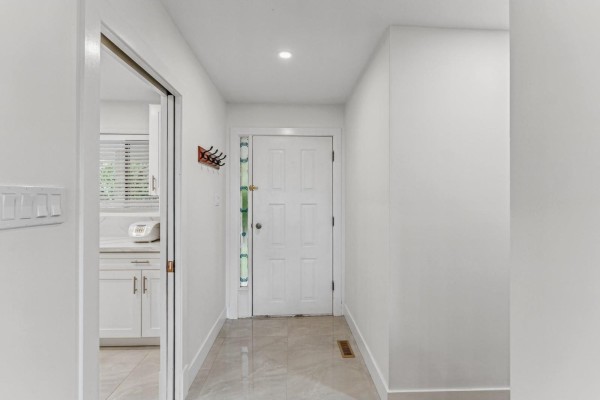 Interior view of a hallway with white walls, tiled floor, and a white door to a kitchen. - 8726 Chilliwack Mountain Road, West Chilliwack, Chilliwack