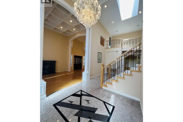 Grand foyer with a coffered ceiling, crystal chandelier, and a view of the living room. - 8740 Minler Road, Richmond