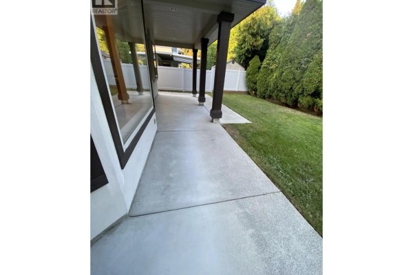 Covered patio with concrete flooring and dark brown columns, overlooking a green lawn. - 8740 Minler Road, Richmond