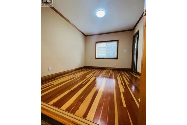 Empty room with glossy hardwood floors featuring a striped pattern and beige walls. - 8740 Minler Road, Richmond