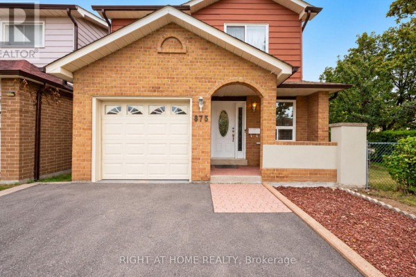 Close-up exterior view of the front entrance, showing the white garage door and brick details. - 875 Messenger Meadow Drive, Mississauga