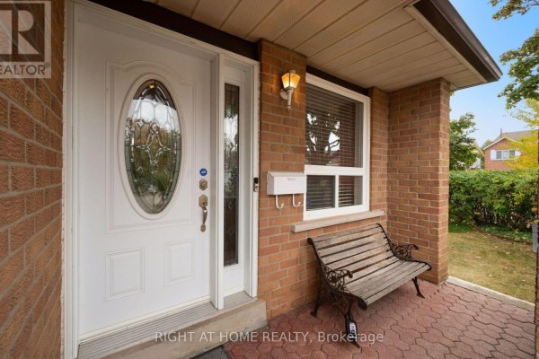 View of the covered front porch with a white door, bench, and brick wall detailing. - 875 Messenger Meadow Drive, Mississauga