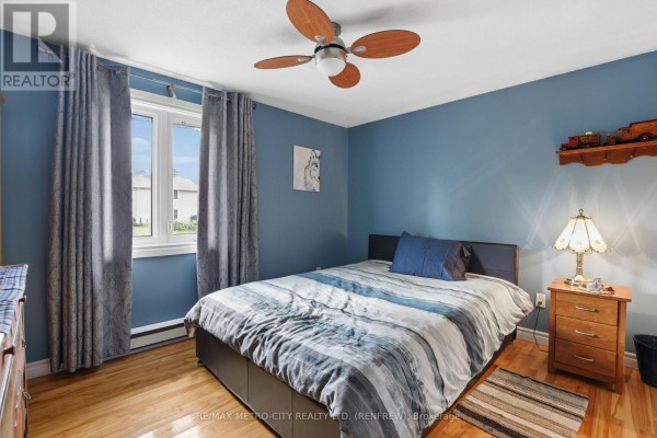 Bedroom with blue walls, ceiling fan, striped bedding, and nightstand with lamp - 876 Hillsview Street Renfrew