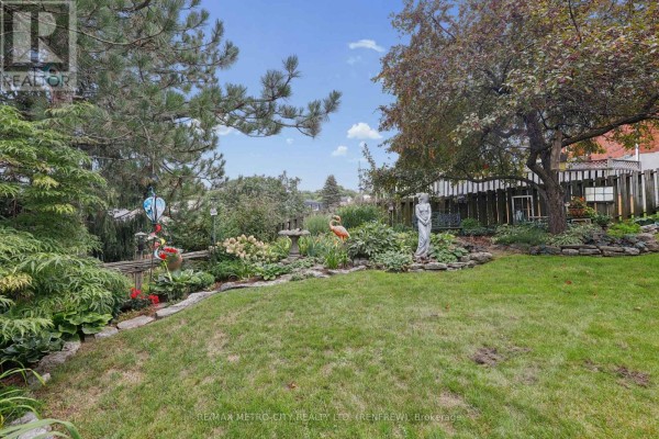 Lush backyard with garden statues, flowers, and trees - 876 Hillsview Street Renfrew