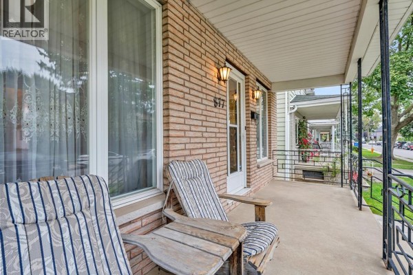 Covered front porch with two chairs and a table, featuring brick and siding. - 877 Pierre Avenue, Windsor