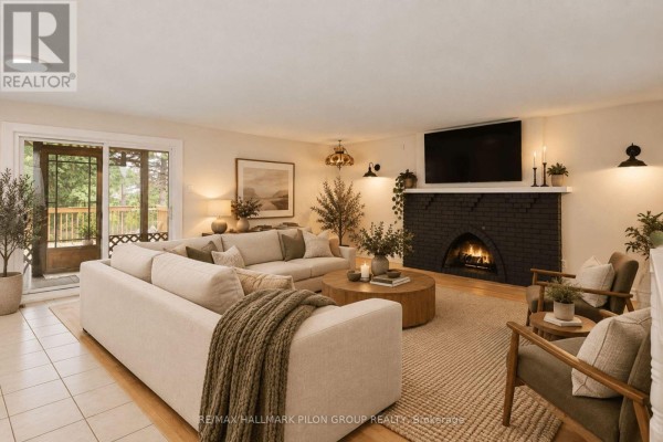 Living room featuring a sectional sofa, black brick fireplace, and wood flooring. - 877 St Felix Road, Clarence Rockland