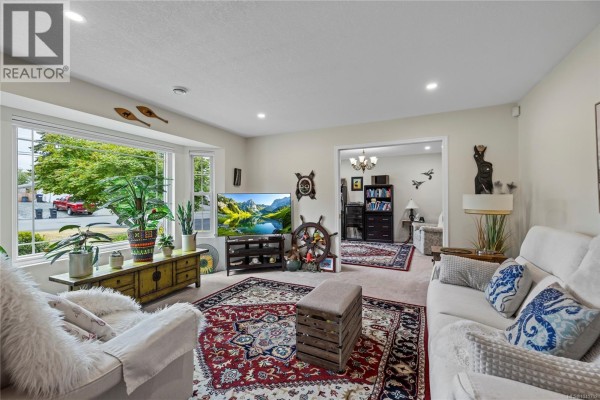 Living room with a large bay window, plush seating, and a nautical theme. - 879 Aberdeen Dr, Parksville
