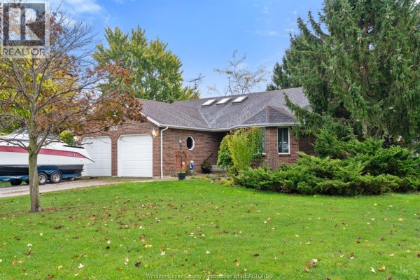 Basement rec room with beige carpet, wood door, and view of distant fireplace. - 879 Road 2 W, Kingsville