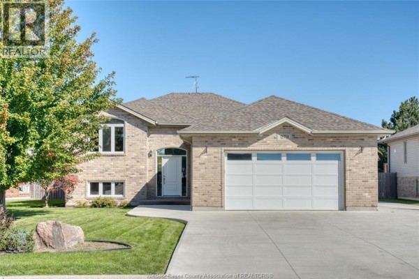 View of a brick house from the side, showing the garage door, front entrance, and lawn. - 879 Westwood, Lakeshore