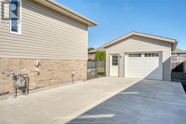 Front view of a beige brick house with a white garage door and attached garage, driveway. - 879 Westwood, Lakeshore