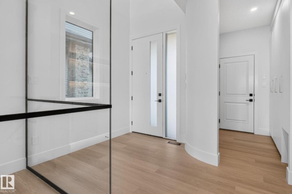 Interior entryway with white walls, double glass front doors, and light wood flooring. - 8791 Mayday Ln Sw, Edmonton