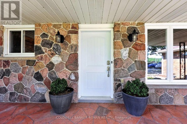 Close-up of the front entrance of the house at 8799 Highway 89, Adjala Tosorontio, featuring a stone facade and a white door. - 8799 Highway 89, Adjala Tosorontio