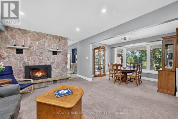 Living room and dining area of the house at 8799 Highway 89, Adjala Tosorontio, with a stone fireplace and a dining table near a window. - 8799 Highway 89, Adjala Tosorontio