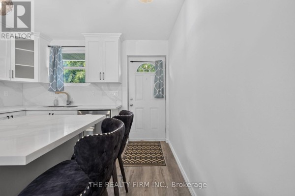 A modern kitchen with white cabinets, stainless steel appliances, and quartz countertops. - 88 - 1919 Trafalgar Street, London East