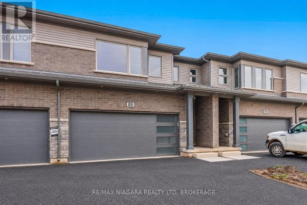 View of townhouse unit 88 exterior with a white truck parked nearby. - 88 - 4552 Portage Road, Niagara Falls