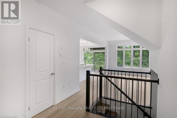 View from upstairs hallway showing a door, staircase, and open concept living area. - 88 - 4552 Portage Road, Niagara Falls