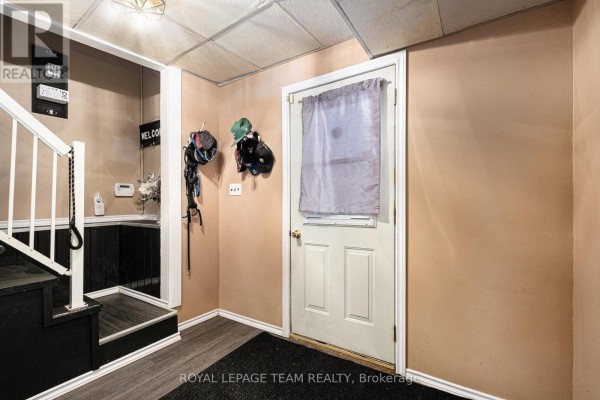 Interior entryway with a white door, textured ceiling, beige walls, and a staircase. - 88 Bay Road, Rideau Lakes