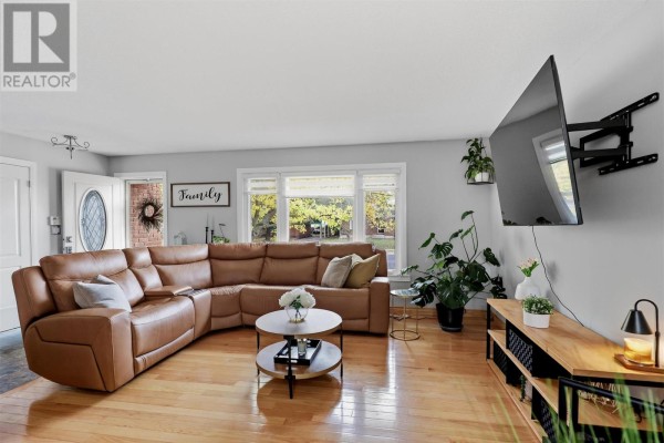 Living room with a brown leather sectional sofa, hardwood floors, and a wall-mounted TV. - 88 Chambers Ave, Sault Ste  Marie
