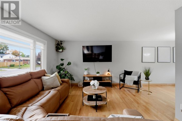Spacious living room with a sectional sofa, large windows, and light grey walls. - 88 Chambers Ave, Sault Ste  Marie