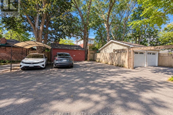 Outdoor parking area with a carport, red garage, and attached double garage doors. - 88 Cowan Avenue, Toronto