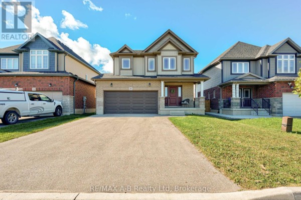 Front view of a two-story residential house with beige siding, brick base, and a dark garage door. - 88 Davidson Drive, Stratford