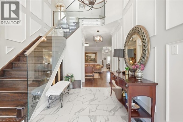 Foyer and living area view showing a staircase, console table, and decorative mirror. - 88 Eringate Court, Stoney Creek