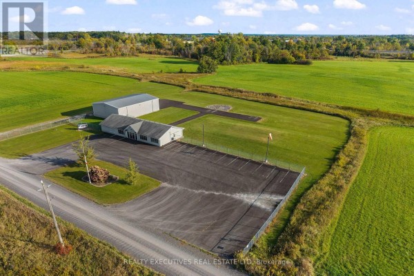 Exterior view of commercial buildings and large hangar on a grassy lot with a paved driveway. - 88 Highway 32 Highway N, Front Of Leeds & Seeleys Bay