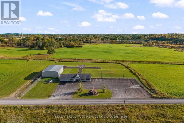 Side view of a commercial building and a metal hangar connected by a paved driveway. - 88 Highway 32 Highway N, Front Of Leeds & Seeleys Bay