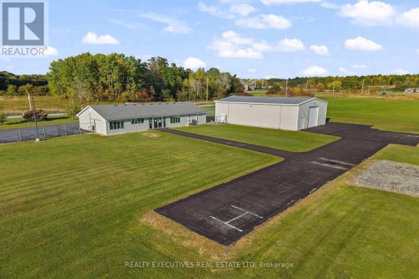 Aerial view of the property showing the hangar, office building, paved access, and expansive green fields. - 88 Highway 32 Highway N, Front Of Leeds & Seeleys Bay