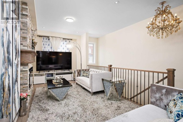 Living room with a plush rug, tufted sofas, fireplace with stone surround, and a chandelier. - 88 Jolly Way S, Toronto