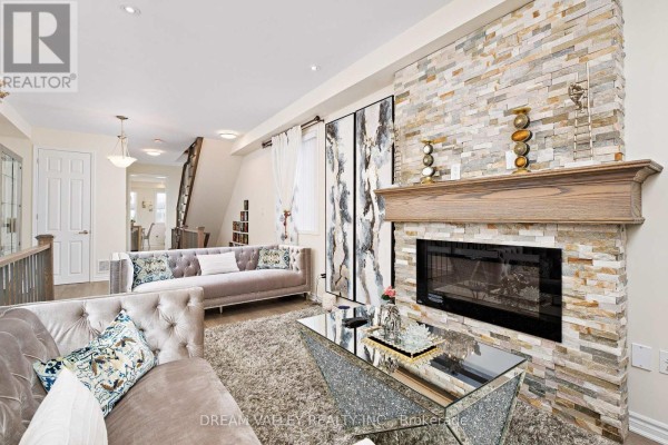 Living room with a large stone fireplace, wooden mantle, sofas, and a glass coffee table. - 88 Jolly Way S, Toronto