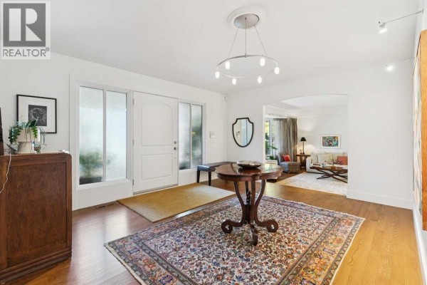 Bright foyer with hardwood floors, a rug, and a console table. - 88 Massey Place Sw, Calgary